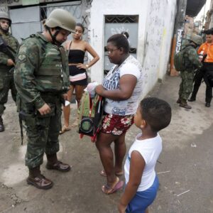 Militar revista mochila de menino durante operação na Favela Kelson's, na Penha